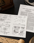 Two vintage patent document pages from the United States Patent Office are displayed on a dark wooden surface, surrounded by retro props including a radio, reel, and wooden objects.