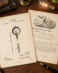 Two vintage patent-style paper documents are arranged on a wooden tabletop with books, a magnifying glass, a pen, and a lit bulb nearby. The left sheet shows a 1890 Edison patent drawing for a light bulb, and the right sheet shows a formal declaration or will with an illustration.