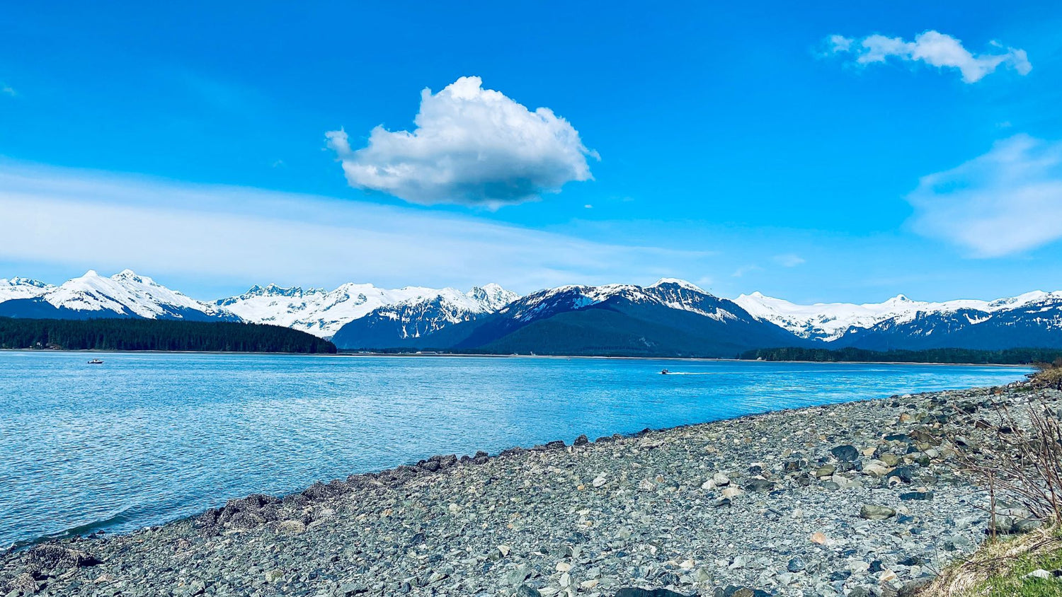 Gray rocks near a body of water under a blue sky during daytime in Douglas, Alaska. - History By Mail